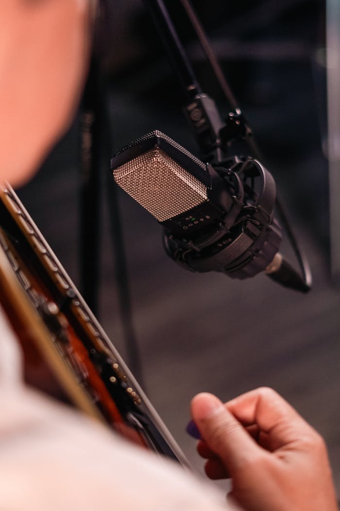 Musician recording acoustic guitar with a professional microphone.